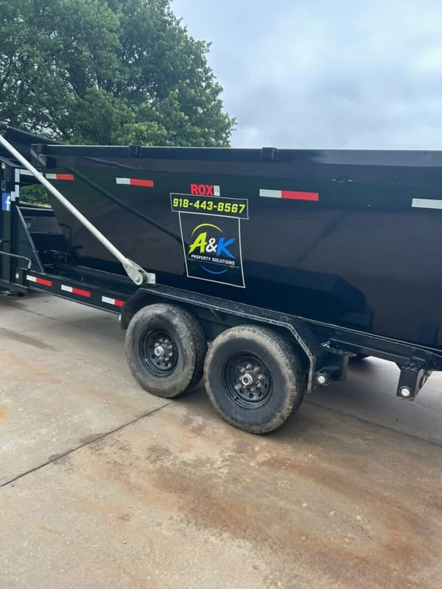 Close-up of the A&K Property Solutions logo decal and phone number on the dumpster