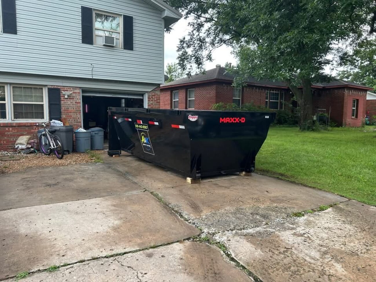 A&K branded 15-yard roll-off dumpster in a residential driveway